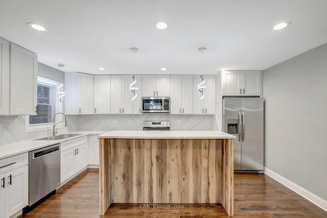 kitchen featuring pendant lighting, stainless steel appliances, a kitchen island, and white cabinets