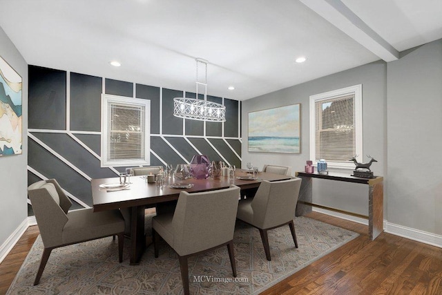 dining area with wood-type flooring, an inviting chandelier, and beam ceiling