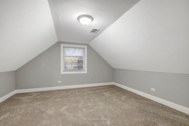 additional living space featuring vaulted ceiling and light colored carpet