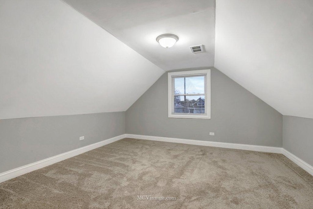 additional living space featuring vaulted ceiling and light carpet