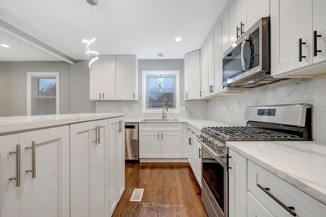 kitchen featuring appliances with stainless steel finishes, sink, hanging light fixtures, and white cabinets