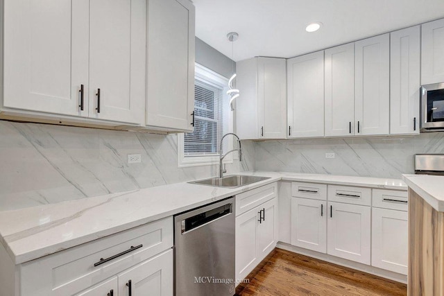 kitchen featuring sink, appliances with stainless steel finishes, white cabinets, pendant lighting, and backsplash