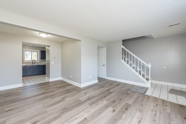 unfurnished living room with sink and light wood-type flooring