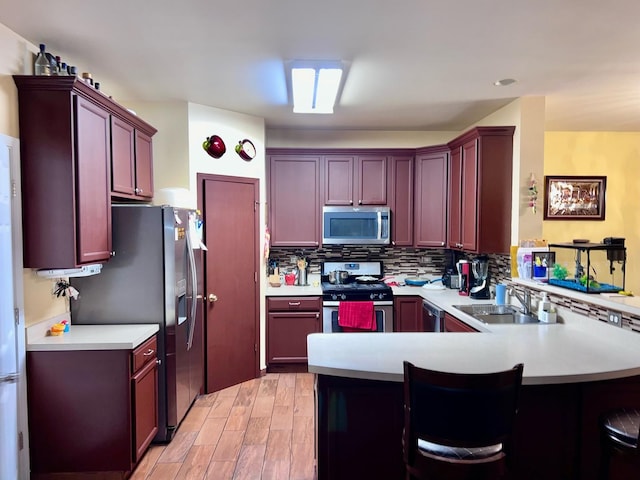 kitchen featuring sink, a breakfast bar area, appliances with stainless steel finishes, kitchen peninsula, and backsplash