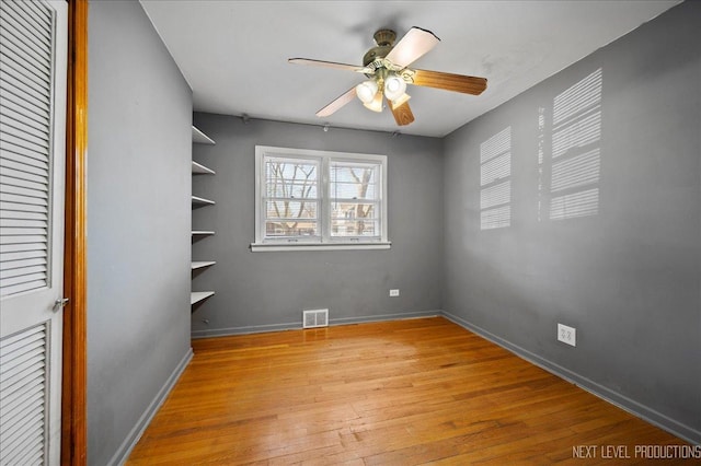 spare room with light wood-style floors, visible vents, ceiling fan, and baseboards