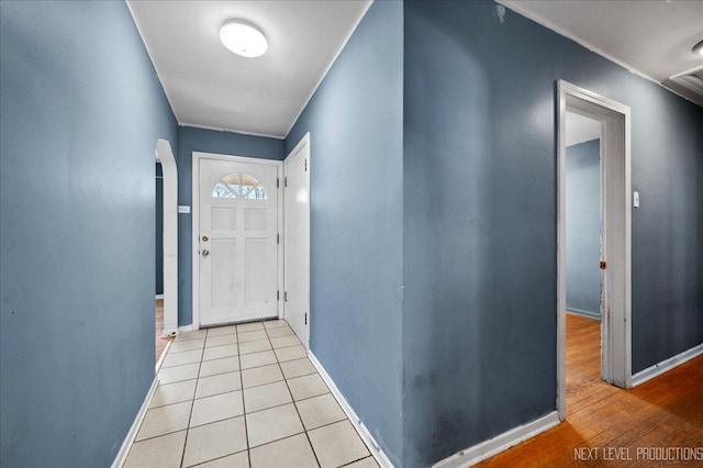 interior space with arched walkways, baseboards, and light tile patterned floors