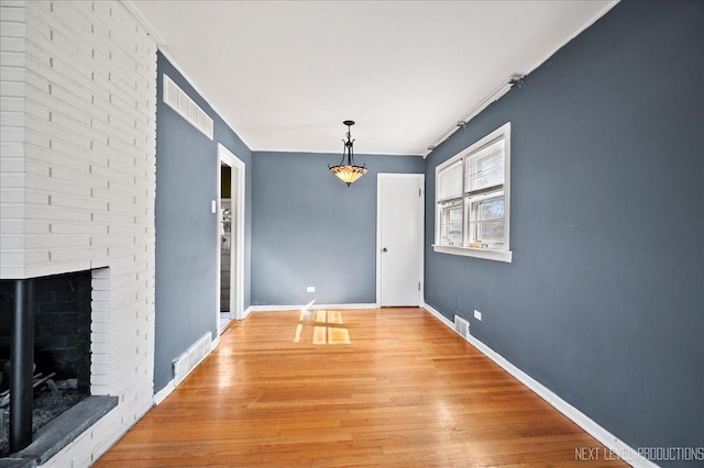 interior space featuring light wood-type flooring, baseboards, a fireplace, and visible vents