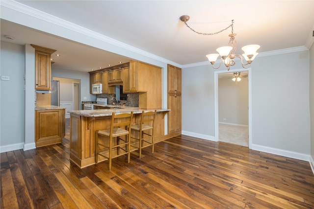 kitchen with white appliances, dark hardwood / wood-style floors, kitchen peninsula, and backsplash