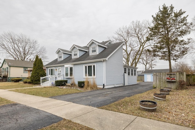 cape cod home featuring a garage, an outdoor structure, and a front yard