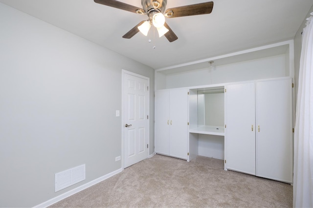 unfurnished bedroom with light carpet, built in desk, and ceiling fan