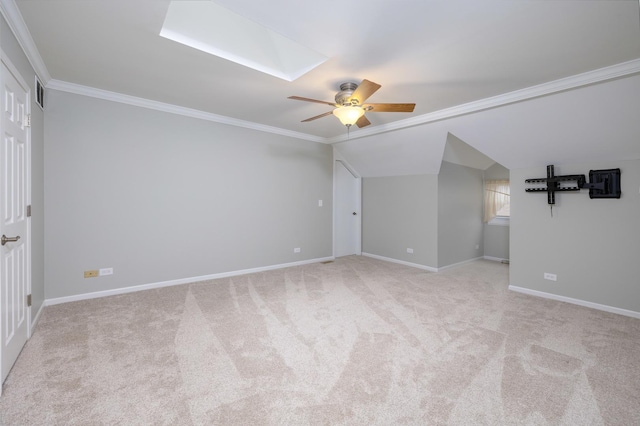 carpeted empty room with crown molding, lofted ceiling with skylight, and ceiling fan