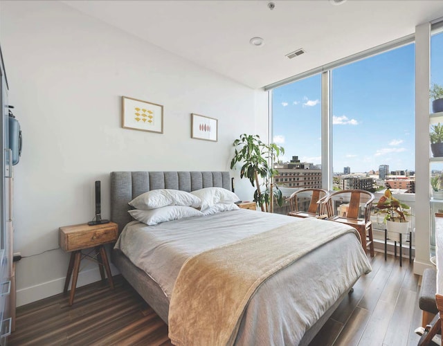 bedroom featuring expansive windows and dark hardwood / wood-style flooring