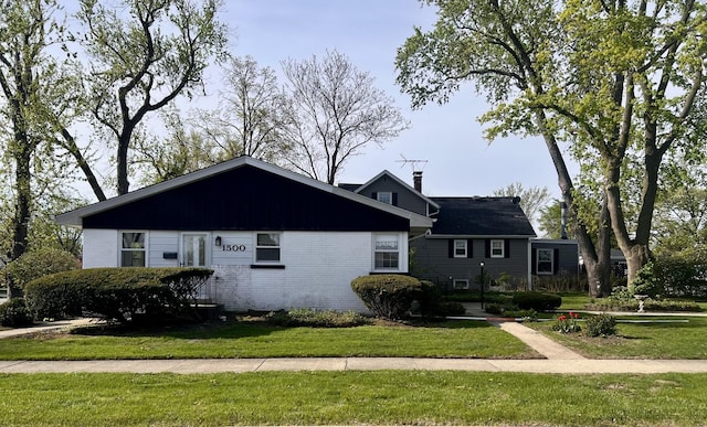 view of front of property featuring brick siding, a front lawn, and a chimney