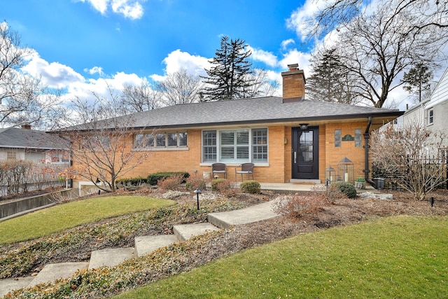 ranch-style house with a shingled roof, a chimney, fence, a front lawn, and brick siding