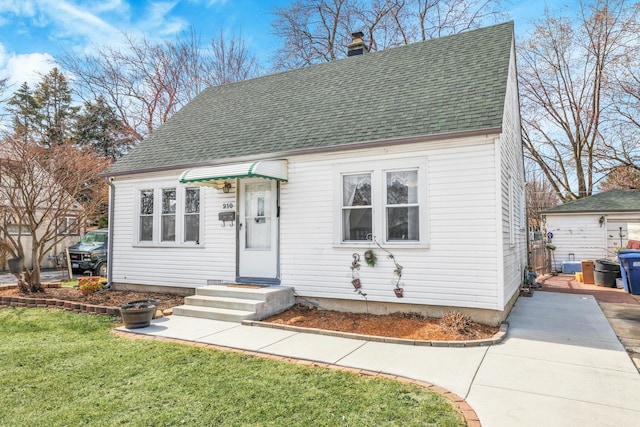 view of front of house featuring a front lawn, a chimney, and roof with shingles