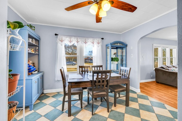 dining space featuring crown molding, plenty of natural light, baseboards, and arched walkways