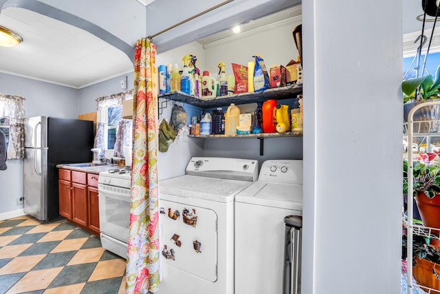 clothes washing area with ornamental molding, washing machine and dryer, arched walkways, light floors, and laundry area