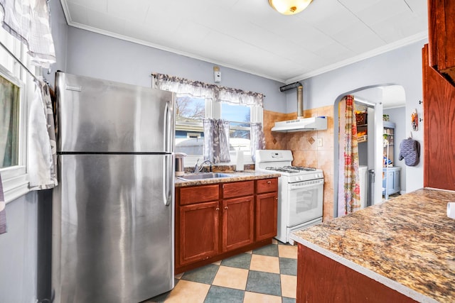 kitchen with light floors, arched walkways, freestanding refrigerator, a sink, and white gas range