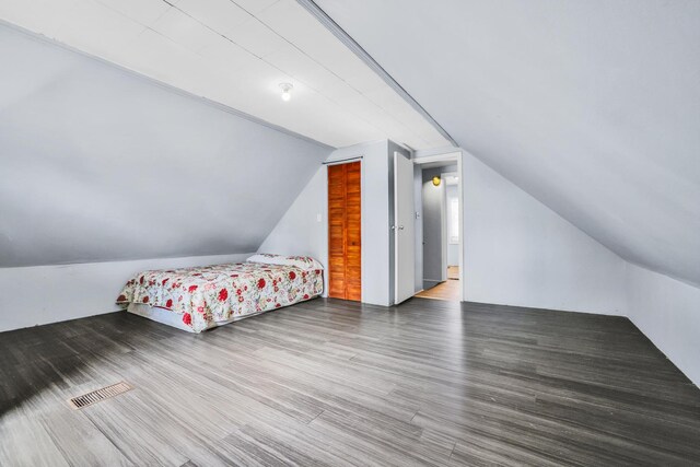 bedroom featuring visible vents, wood finished floors, and vaulted ceiling