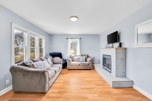 living room with a wealth of natural light, light wood-type flooring, and a fireplace