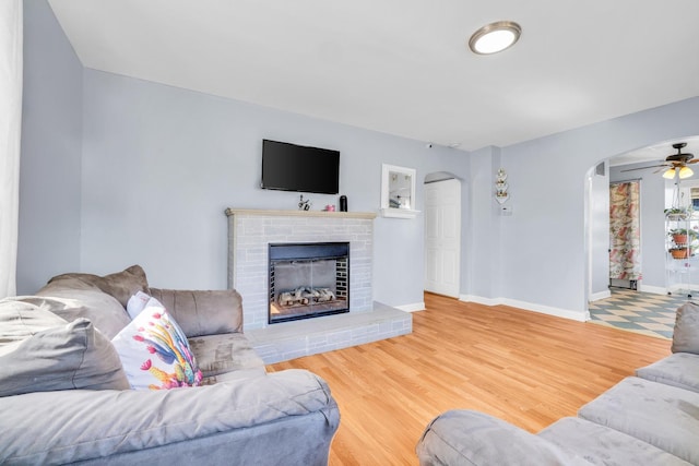 living room with baseboards, arched walkways, wood finished floors, and a fireplace