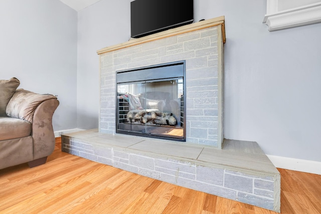 room details featuring a multi sided fireplace, baseboards, and wood finished floors