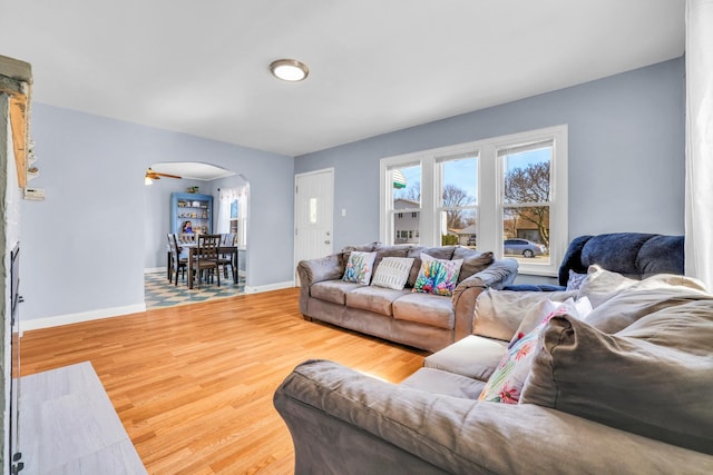 living room with wood finished floors, arched walkways, and baseboards