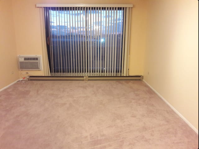 empty room featuring light carpet and an AC wall unit