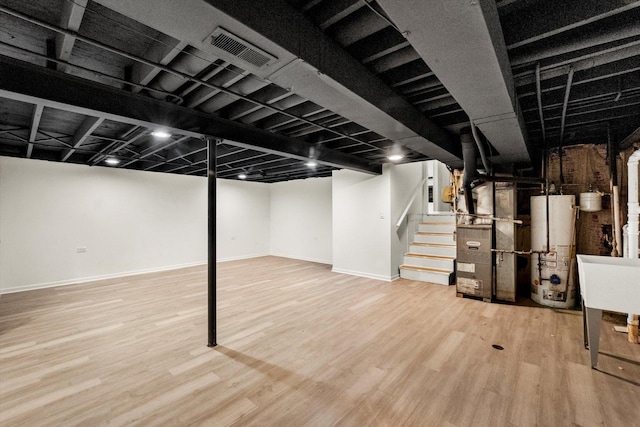 basement featuring heating unit, light hardwood / wood-style floors, and water heater