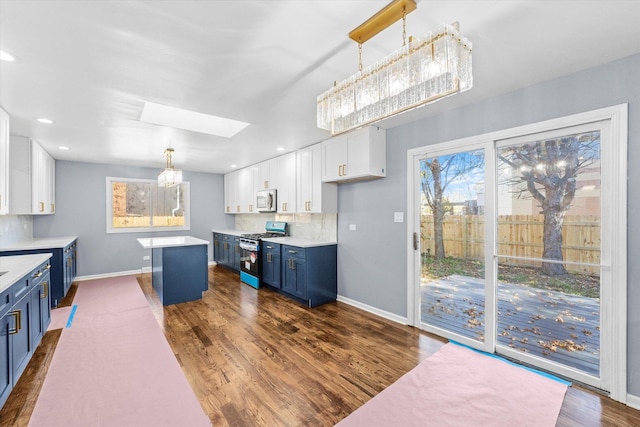 kitchen featuring stainless steel appliances, hanging light fixtures, blue cabinets, and white cabinets