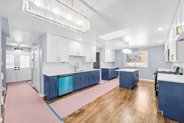 kitchen with blue cabinetry, sink, appliances with stainless steel finishes, a kitchen island, and white cabinets