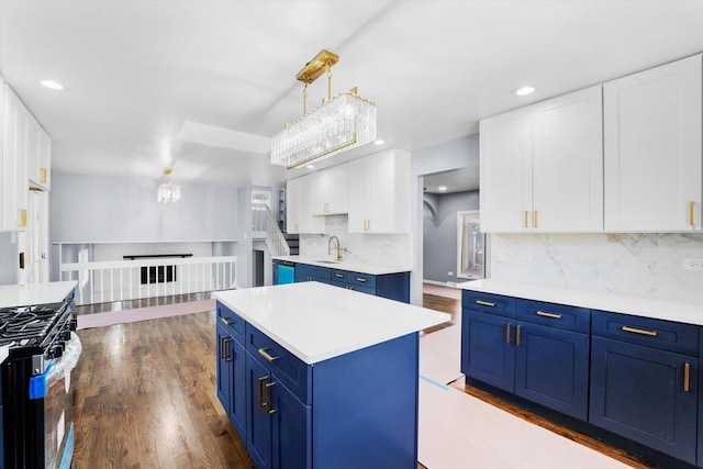 kitchen featuring blue cabinets, hanging light fixtures, stainless steel range with gas cooktop, a kitchen island, and white cabinets