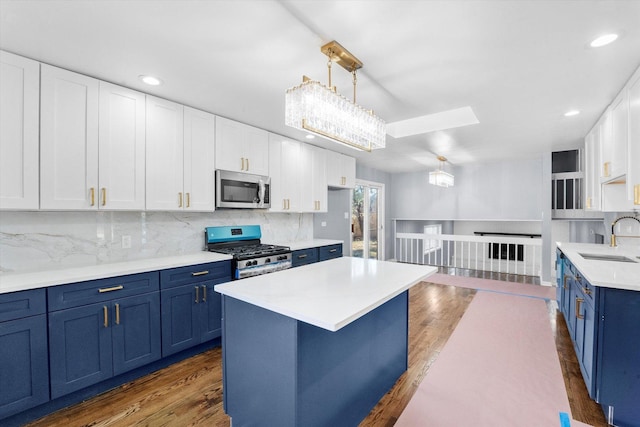 kitchen featuring blue cabinetry, sink, pendant lighting, stainless steel appliances, and white cabinets