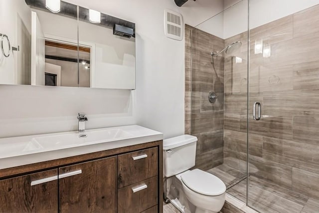 bathroom with vanity, toilet, and a shower with shower door