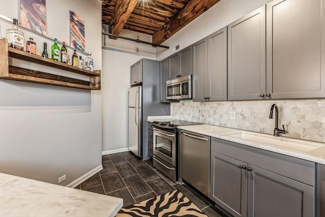 kitchen featuring tasteful backsplash, stainless steel appliances, gray cabinets, and sink