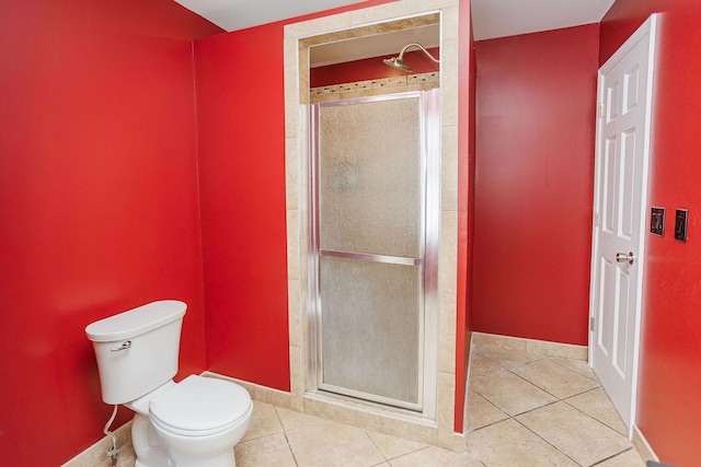 bathroom featuring a stall shower, tile patterned flooring, baseboards, and toilet