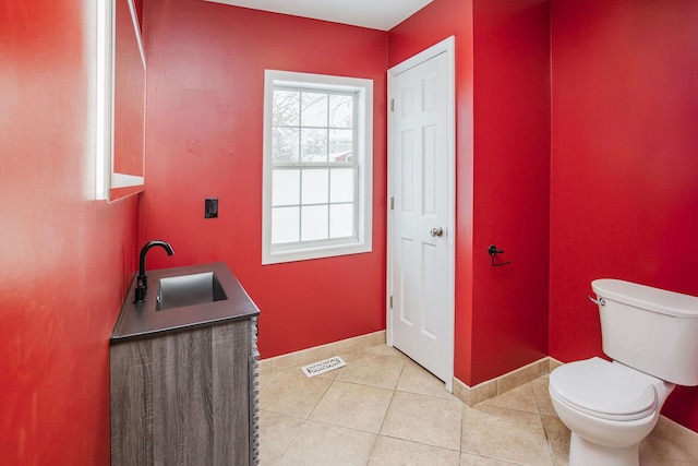 bathroom featuring visible vents, toilet, a sink, baseboards, and tile patterned floors