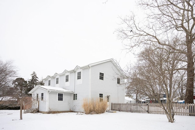 snow covered property with entry steps and fence