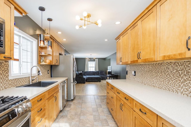 kitchen featuring a notable chandelier, light countertops, appliances with stainless steel finishes, open floor plan, and a sink