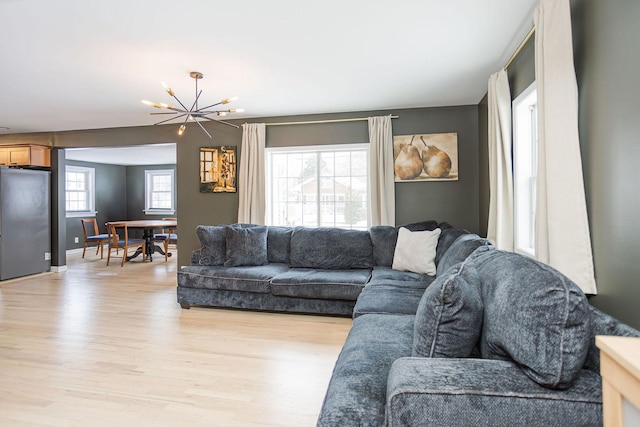 living area featuring light wood-style flooring, a chandelier, and baseboards