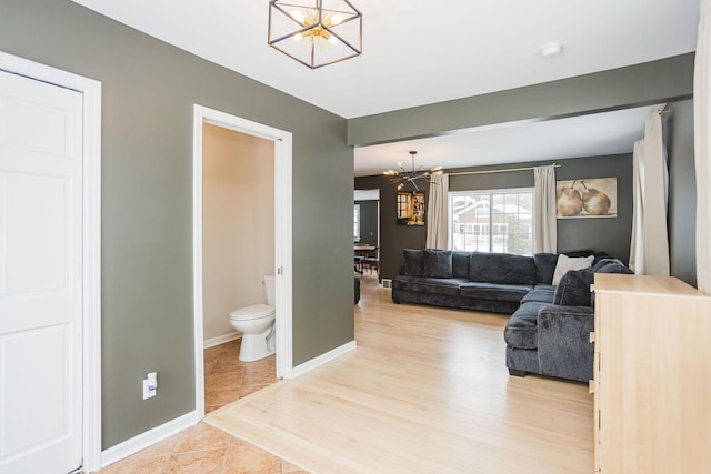 living room featuring wood finished floors, baseboards, and an inviting chandelier