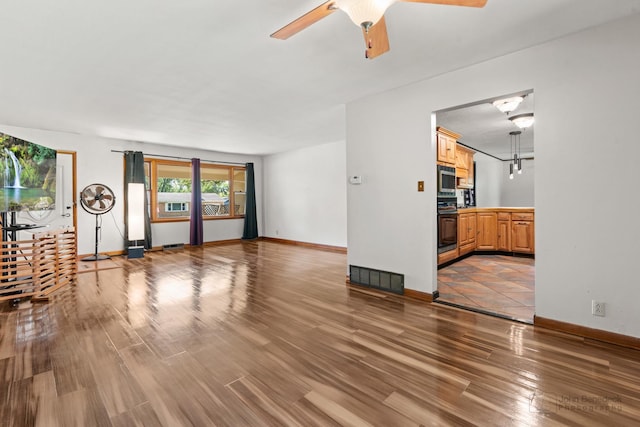 unfurnished living room with ceiling fan and wood-type flooring