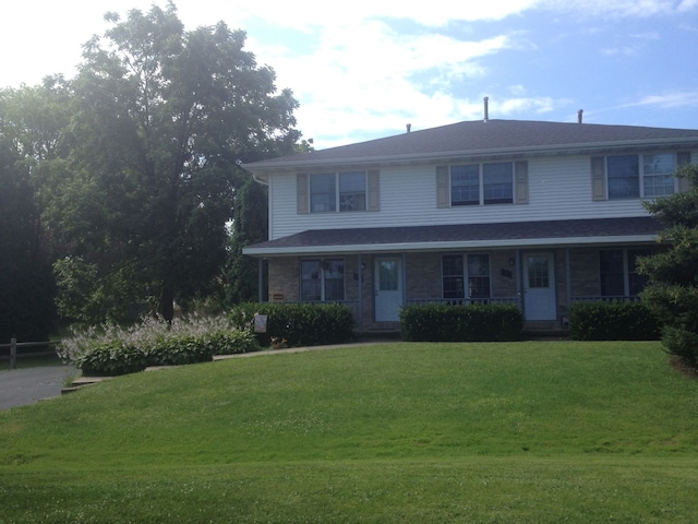 view of property featuring covered porch and a front yard