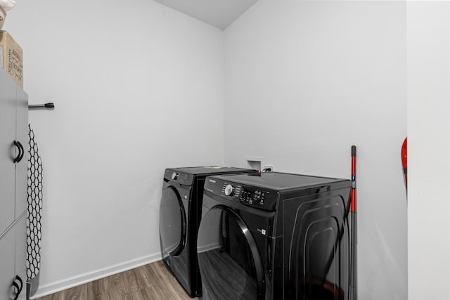 clothes washing area featuring hardwood / wood-style flooring and washing machine and clothes dryer