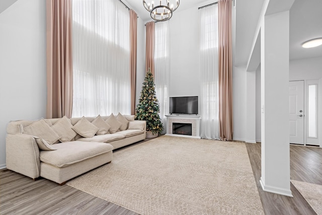 living room with hardwood / wood-style flooring, a towering ceiling, and a notable chandelier