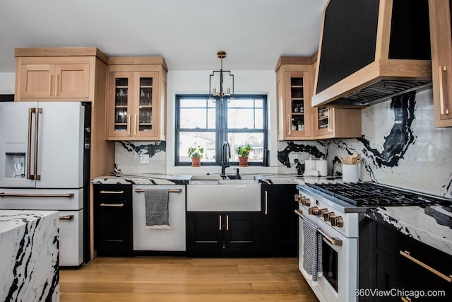 kitchen with premium appliances, dark cabinets, a sink, custom exhaust hood, and pendant lighting