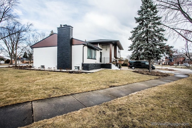 view of side of home with a yard and a chimney