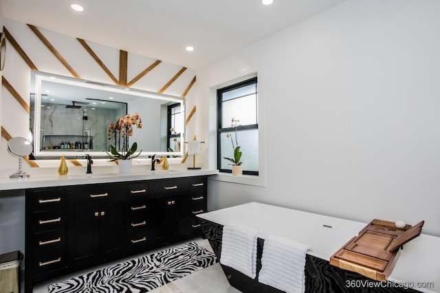 bathroom featuring a sink, double vanity, a marble finish shower, and recessed lighting