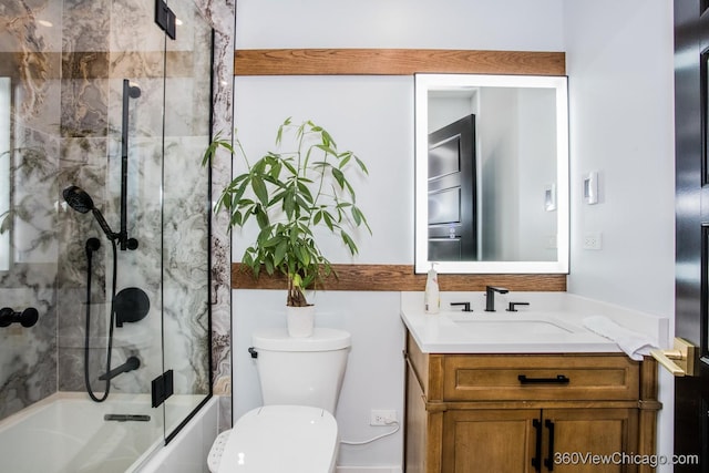 bathroom featuring toilet, combined bath / shower with glass door, and vanity