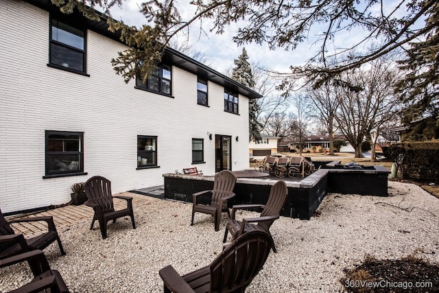 rear view of house featuring an outdoor fire pit, brick siding, and a patio